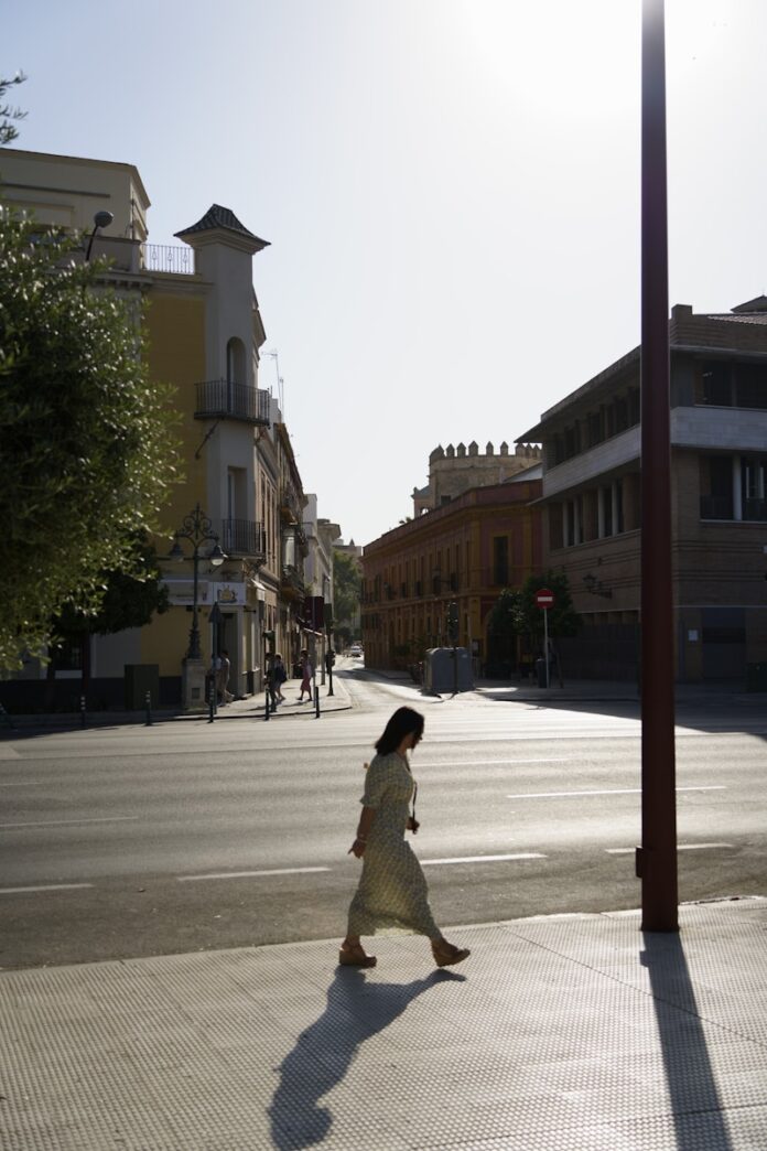 A woman walking down a street next to tall buildings